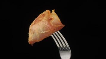 A piece of chicken on a fork with a black background video
