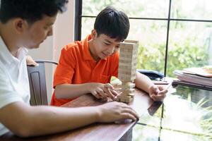 asian father and son playing with jenga tower photo
