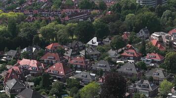 Aerial view of a residential area in Eindhoven, Netherlands, with red tiled rooftops, tree lined streets, and a smooth drone motion capturing the neighborhood. video