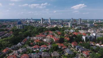 A slow drone flight over Eindhoven, Netherlands, reveals red roofed houses, high rise buildings, green spaces, and a vibrant cityscape under a clear sky. video