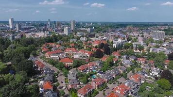 A slow drone flight over Eindhoven, Netherlands, reveals red roofed houses, modern buildings, a church spire, greenery, and a clear blue sky. video