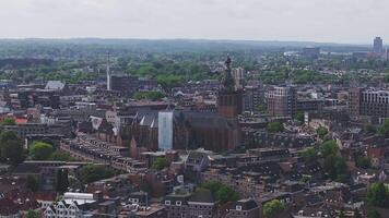 A slow sweeping aerial pan of Nijmegen, Netherlands, showing red roofed buildings, modern structures, greenery, and a clear horizon. video
