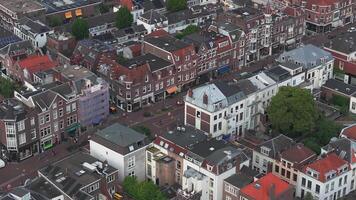 Aerial view of a street in Utrecht, Netherlands, featuring gabled roofs, red and white facades, trees, bicycles, pedestrians, and moving vehicles. video