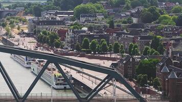 Aerial view of Nijmegen, Netherlands, showing the Waal River, a steel bridge, a moving cargo ship, a harbor, and urban and rural landscapes. video