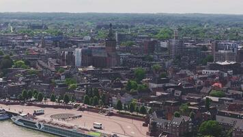 Aerial view of Nijmegen, Netherlands, featuring Stevenskerk, traditional Dutch buildings, modern structures, greenery, and distant rolling hills. video