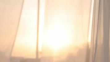 Light breezy sheer curtain blowing in the wind with sunset behind it video