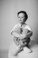 Black and white image of a laughing boy mid motion, caught candidly in a moment of joy, light background with soft shadows gives a timeless feel. photo