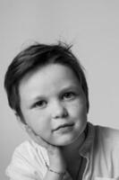Monochrome close up of a young boys face in a studio setting, serious gaze, side lighting highlights the texture of his skin and hair, minimalist composition. photo