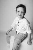 Formal portrait of a small boy wearing suspenders and a bow tie, standing straight with hands in pockets, classic studio light setup with clear detail and contrast. photo