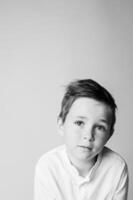 Studio portrait of a young boy holding a toy airplane, looking slightly away with a quiet smile. High contrast lighting emphasizes the nostalgic, timeless mood. photo