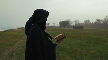 Cloaked figure with a book video
