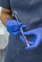 Close-up of dentist hands holding a syringe with a solution photo