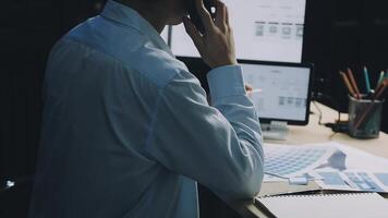 A man is sitting at a desk with a laptop and a phone video