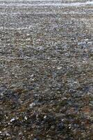 Flowing shallow water with ripples and rocks underneath photo