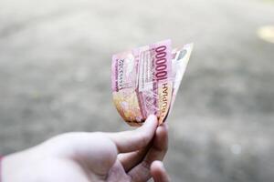 woman shows one hundred thousand rupiah money photo