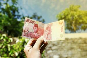 one hundred thousand rupiah against the backdrop of the sky shows the concept of success photo