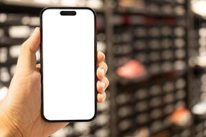Hand Holding Blank Smartphone Screen in Retail Store. Mobile shopping, online commerce, in-store digital experiences, product information lookup, or advertising. photo