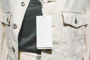 Blank Price Tag on Casual Clothing. The blank tag offers ample copy space, making it ideal for concepts related to fashion, sales, pricing, and retail. photo