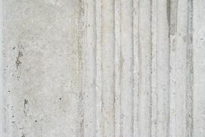 Textured Concrete Surface with Vertical Grooves. A detailed shot of a light grey concrete wall featuring a series of parallel vertical grooves. photo