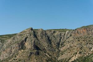 A plane flying over a mountain with a blue sky photo