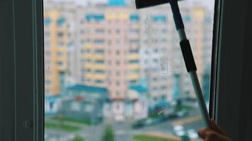 Brush cleaning dirty window with water and soap. Washing glass window inside on city building background. video