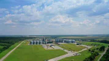 Modern industrial plant on green field. Agricultural factory with grain elevators among summer nature. Panoramic view. View from the air. video