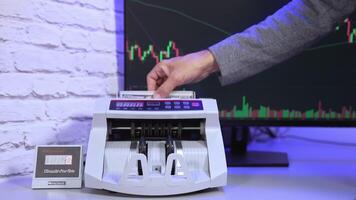Modern counter machine on large monitor background. Man's hand putting paper money into a counting machine and takes them after financial operation. video