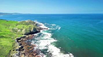 A breathtaking aerial view showcasing a vibrant coastline characterized by lush greenery and powerful crashing waves video