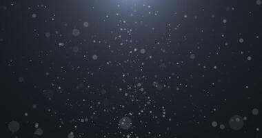 lentamente caindo, rodando, e espumante bokeh partículas dentro branco luz contra uma Sombrio fundo. abstrato neve.414 video