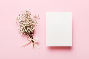 Wedding mockup with white paper list and flowers gypsophila on colored table top view flat lay. Blank greeting cards and envelopes photo
