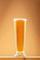 Pint of bright golden beer with light foam on wooden plank in warm ambient light. Concept of beer refreshment and lager clarity. Tall glass of golden beer with foam on top on wooden surface photo