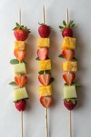 Three Colorful Fruit Skewers with Strawberries, Pineapple, and Cantaloupe photo