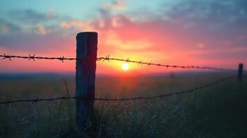 A sunset over a field with barbed wire photo
