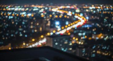 Defocused city nightscape with vibrant bokeh lights and blurry traffic trails on a winding road photo