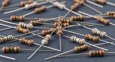 Close up of electronic resistors scattered on a dark blue surface for circuit board assembly photo