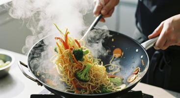 Professional chef tossing fresh vegetable stir fry noodles with steam in a hot wok photo