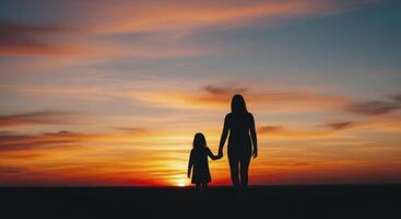 Silhouette of a mother and daughter holding hands walking at sunset photo