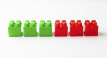 Bright green and red plastic construction blocks neatly aligned on a simple white studio surface. photo