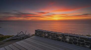Vibrant sunset over serene ocean from cliffside observation deck photo