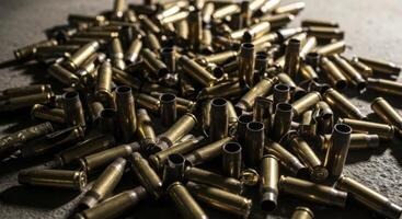 Large pile of spent brass shell casings scattered on a dark concrete surface photo
