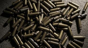 Large pile of spent brass shell casings on a dark textured surface photo