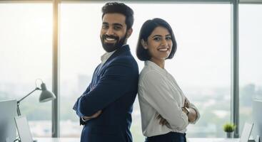 Young indian business professionals standing back to back in modern office smiling photo