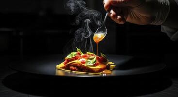 Gloved chef hand drizzling sauce over steaming gourmet pasta dish on black plate photo