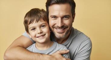 A proud father and his young son smiling cheerfully, sharing a strong embrace on a yellow background. photo