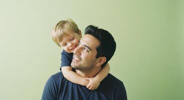 Heartwarming studio portrait of a joyful young father and his small son on a light green background. photo