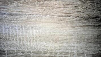 Closeup of a light, weathered wood texture featuring fine horizontal grain lines and a faint grid pattern. The surface shows signs of wear, adding character and depth. photo