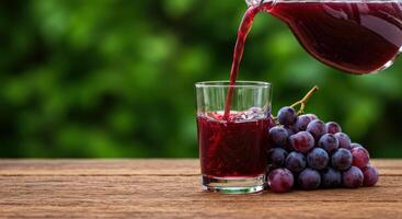 Pouring grape juice into glass next to a fresh grape bunch for a healthy and delicious drink photo