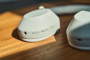 Large white wireless headphones lying on a wooden table photo