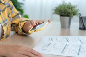 Modern female use phone to scan barcode or QR codes to pay credit card bill after receive document invoice. payment, receive, paying electricity, digital payments without money, technology, scan photo