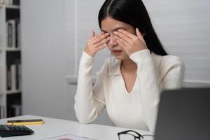 Eye problems, Asian women with tired and irritated eyes, eye rubbing, dry, eye pain after work, migraine, headache, blurred vision, photophobia, working in the dark, photo